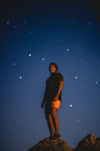 Low angle view of young woman standing on rock