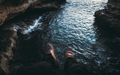 Low section of man standing on rock by sea
