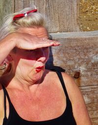 Close-up of mature woman shielding eyes during sunny day