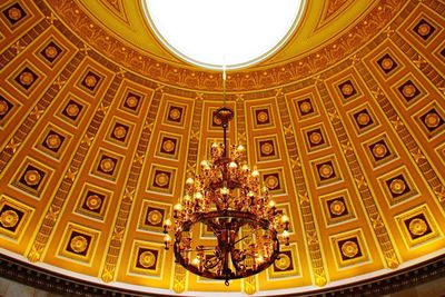 Low angle view of chandelier hanging by ornate ceiling in capitol building