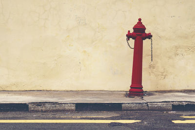 Red fire hydrant on sidewalk against wall