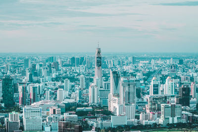 High angle view of city buildings against cloudy sky