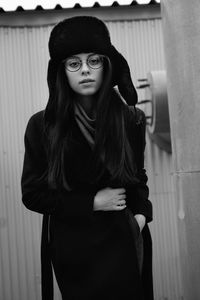 Portrait of a young woman standing against wall