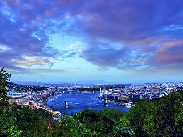 sky, architecture, built structure, city, cloud - sky, building exterior, tree, water, cityscape, high angle view, transportation, sea, cloudy, cloud, river, nautical vessel, city life, blue, panoramic, bridge - man made structure