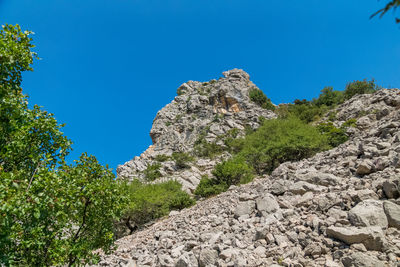 Low angle view of rock formation against clear blue sky