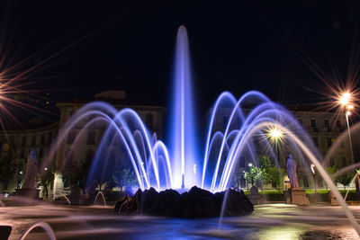 Illuminated fountain in city at night