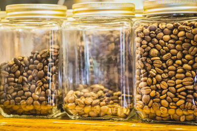 Close-up of coffee beans in glass containers on table