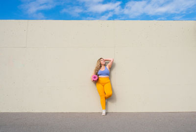 Full length of woman standing against wall