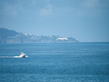 Travelling speedboat on overcast day with bray town in the background on the coast.