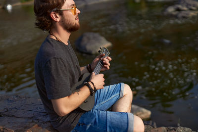 Young man sitting by lake