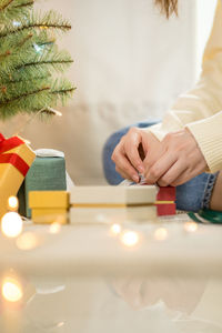 Woman hand tieding ribbon new year gift box and decorate christmas tree