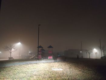 Illuminated street lights on field against clear sky at night