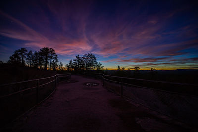 Road amidst trees against sky during sunset