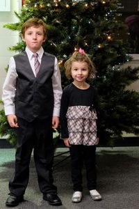 Portrait of boy and girl standing against christmas tree