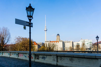 Communications tower in city against clear blue sky