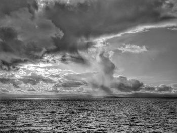 View across lake of storm clouds and rain. mountain silhouette. sun backlighting. 