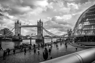 People walking on promenade against tower bridge in city