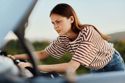 Side view of young woman sitting in car