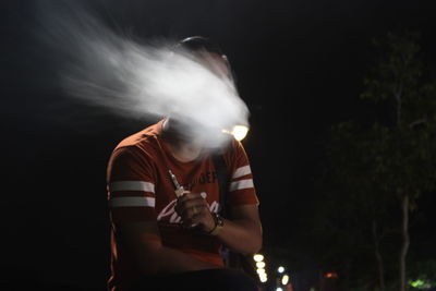 Man smoking against black background