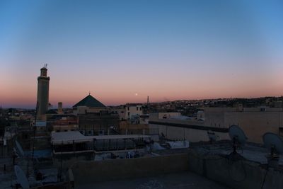 Buildings in city against clear sky during sunset