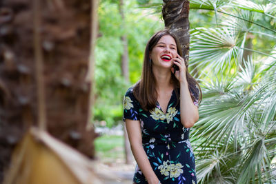 Young woman smiling while standing against trees