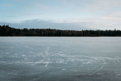 Frozen lake with trees off in the distance in winter.
