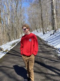 Full body of teen boy standing in road on snow day 