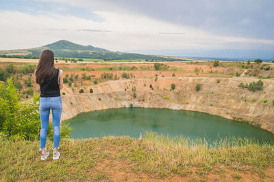 Rear view of woman standing on landscape against sky