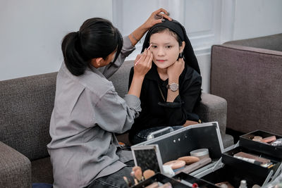 Young woman using phone while sitting at home