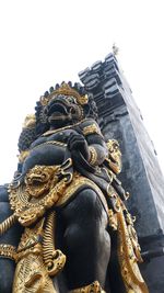 Low angle view of statue against historic building against sky