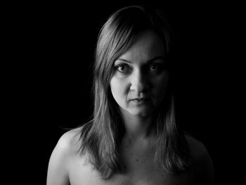 Close-up portrait of young woman against black background