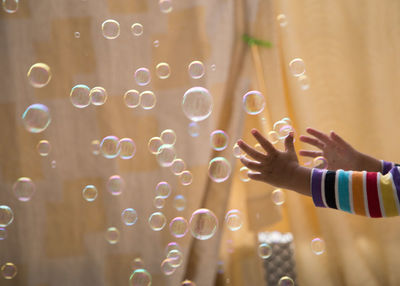 Cropped hands of child by bubbles