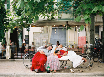 People sitting on street against buildings