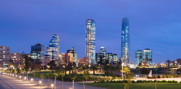 Illuminated cityscape against clear blue sky