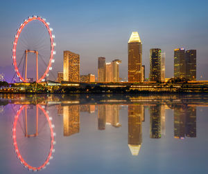 Reflection of illuminated ferris wheel in river against sky