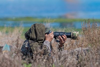 Man photographing on land against lake