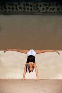 Full length of woman with arms raised on sand