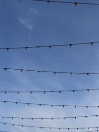 Low angle view of power lines against blue sky