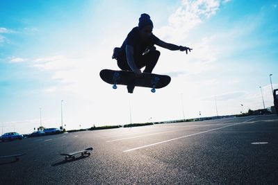 Low angle view of man in mid-air on skateboard on sunny day
