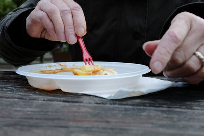 Midsection of man holding ice cream in bowl on table