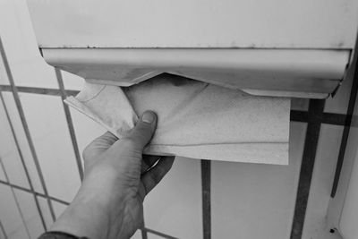 Cropped image of person removing facial tissue in bathroom