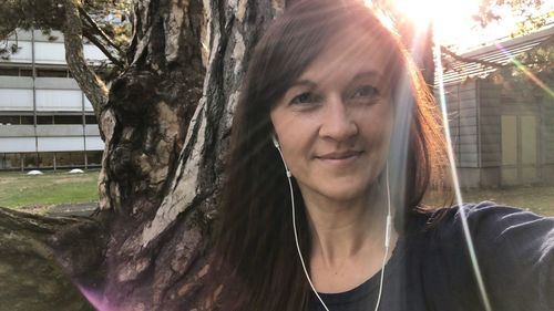 Portrait of smiling woman against tree trunk