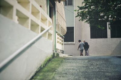 Rear view of couple walking on building
