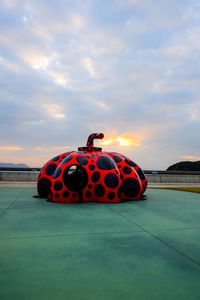 Red umbrella on illuminated car against sky during sunset