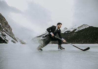 Hockey player on frozen lake in suit stops fast and sprays ice