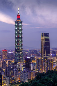 Illuminated taipei 101 in city against cloudy sky