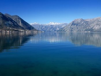 Scenic view of lake and mountains against clear blue sky