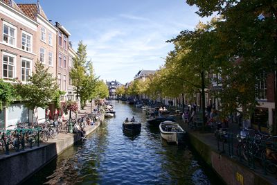 Boats in canal amidst buildings in city against sky