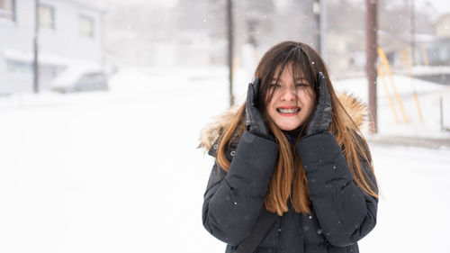 Portrait of smiling woman standing in snow