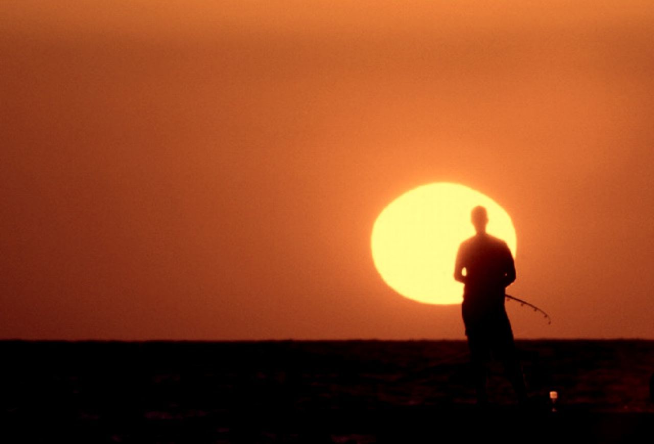 sunset, silhouette, orange color, copy space, lifestyles, leisure activity, sun, men, standing, clear sky, landscape, beauty in nature, tranquil scene, nature, scenics, field, sky, side view